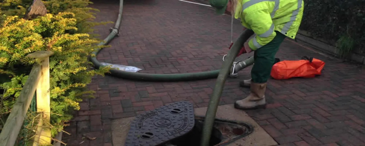 Septic tank cleaning technician servicing a septic tank with a vacuum hose in Albuquerque, NM