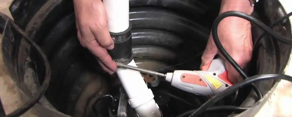 Sump pump installation technician connecting PVC discharge piping in Albuquerque, NM